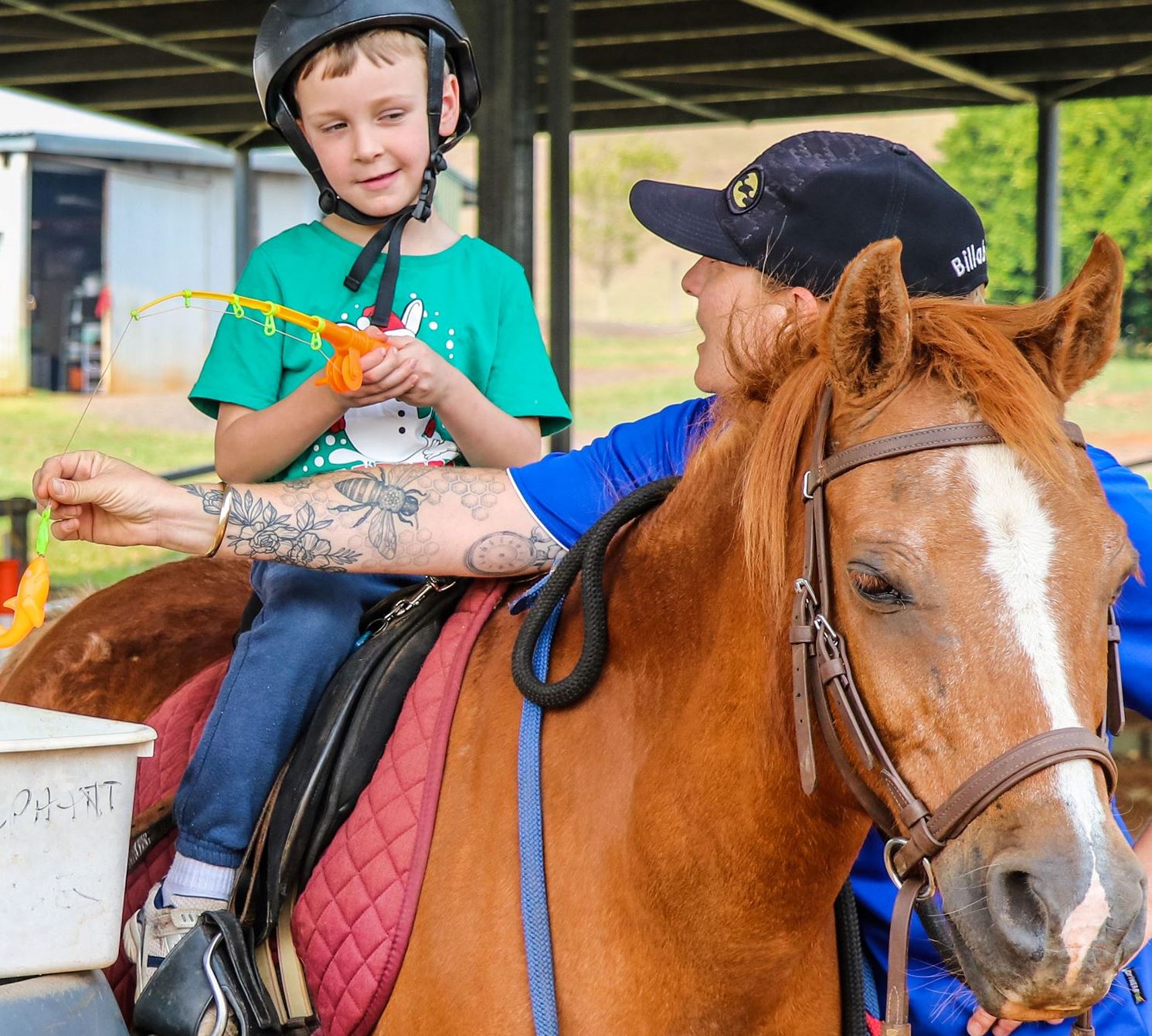 Young disabled boy and volunteer, learning skills and activities surrounding horses.